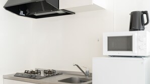 A kitchen with a gas stove, a sink, a microwave, and a kettle on the stove. - ILIMA Higashi Nakano (Tokyo)