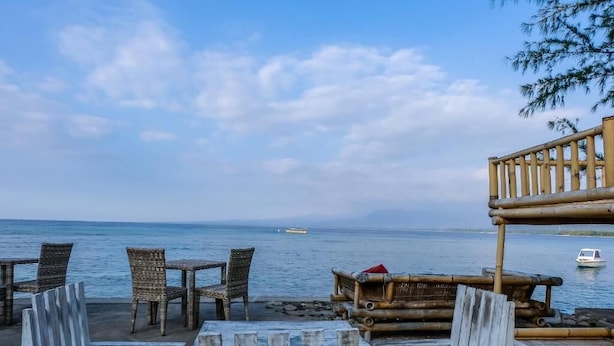 A beachside seating area with wicker chairs and a wooden deck overlooking the sea. - Nelly Bungalows (Gili Air)
