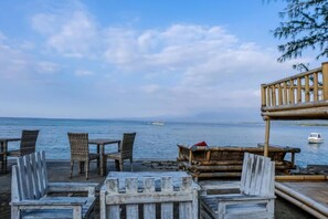 A beachside seating area with wicker chairs and a wooden deck overlooking the sea.