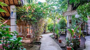 A garden pathway with potted plants and a wooden sign indicating breakfast time. - Nelly Bungalows (Gili Air)