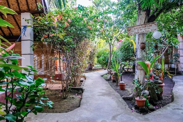 A garden pathway with potted plants and a wooden sign indicating breakfast time.