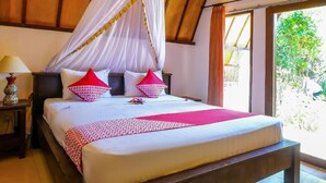 A bed with a canopy, pillows, and a bedside table with a lamp. - Nelly Bungalows (Gili Air)