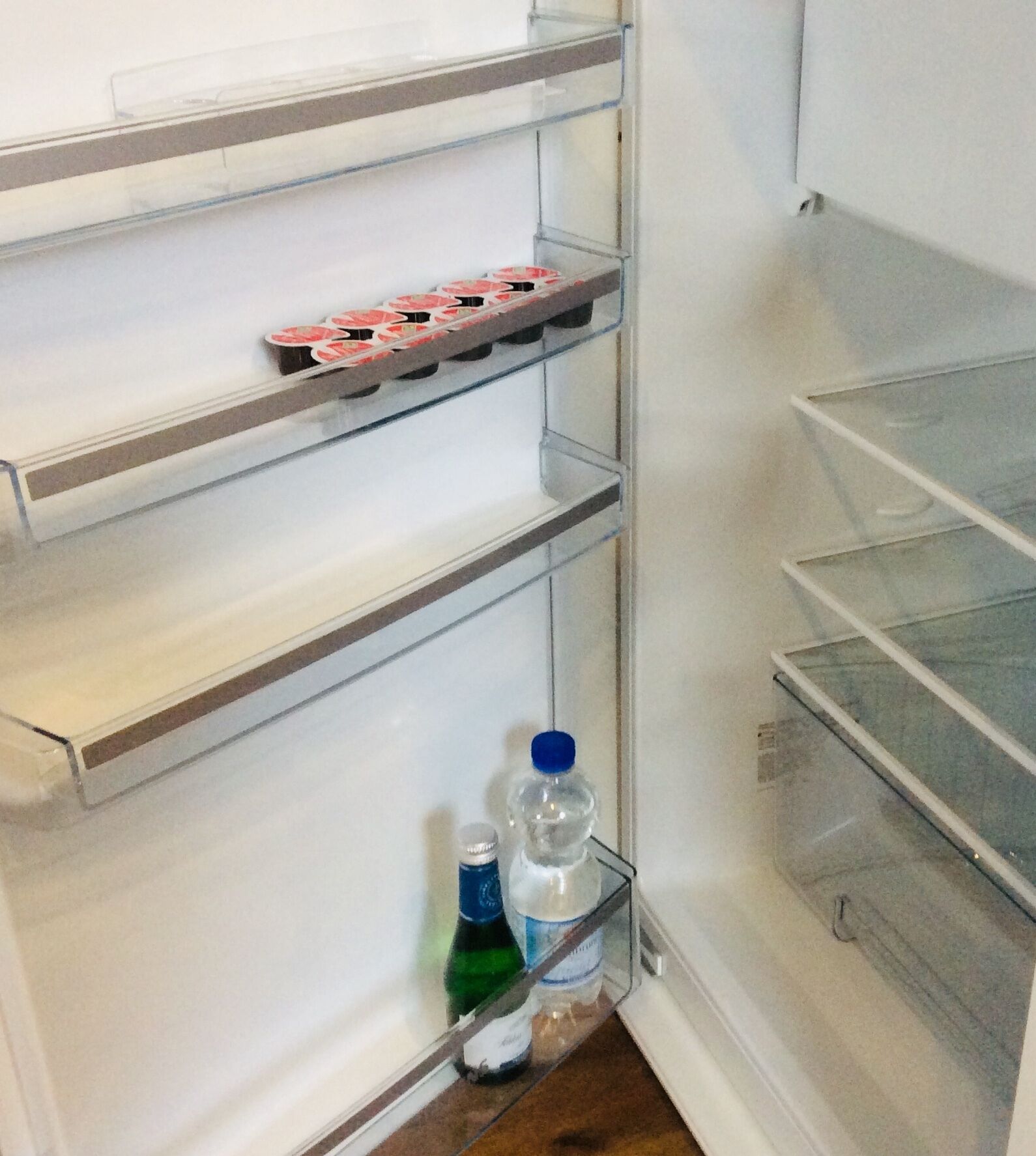 A refrigerator with multiple shelves, some containing items like bottles and a tray of food containers.