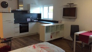 A compact kitchen with a stove, sink, and a small dining area with a table and chairs. - Vacation apartment "Fernblick " (ZWEIBRÜCKEN)