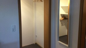 A narrow hallway with a door leading to a room with a closet and a mirror. - Vacation apartment "Fernblick " (ZWEIBRÜCKEN)