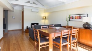 Uma sala de jantar moderna com mesa e cadeiras de madeira, um sofá e um abajur.