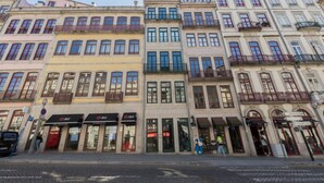Uma fileira de edifícios altos com lojas no térreo, incluindo uma placa visível 'JLL'.