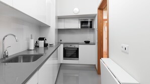Uma cozinha moderna com uma pia de aço inoxidável, forno embutido e micro-ondas.