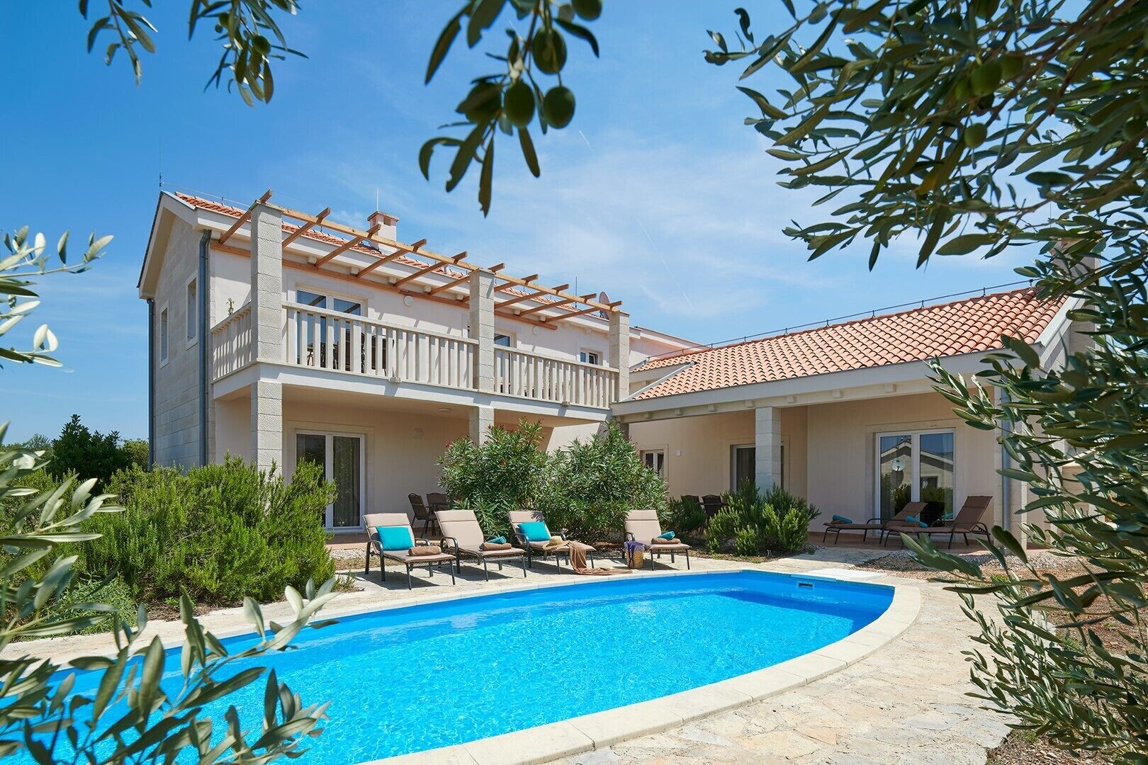 A two-story building with a swimming pool, outdoor seating, and a pergola.