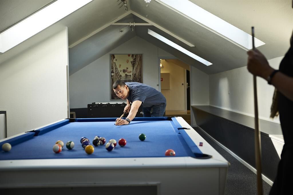 A pool table in a room with a sloped ceiling and skylights.