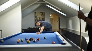 A pool table in a room with a sloped ceiling and skylights.