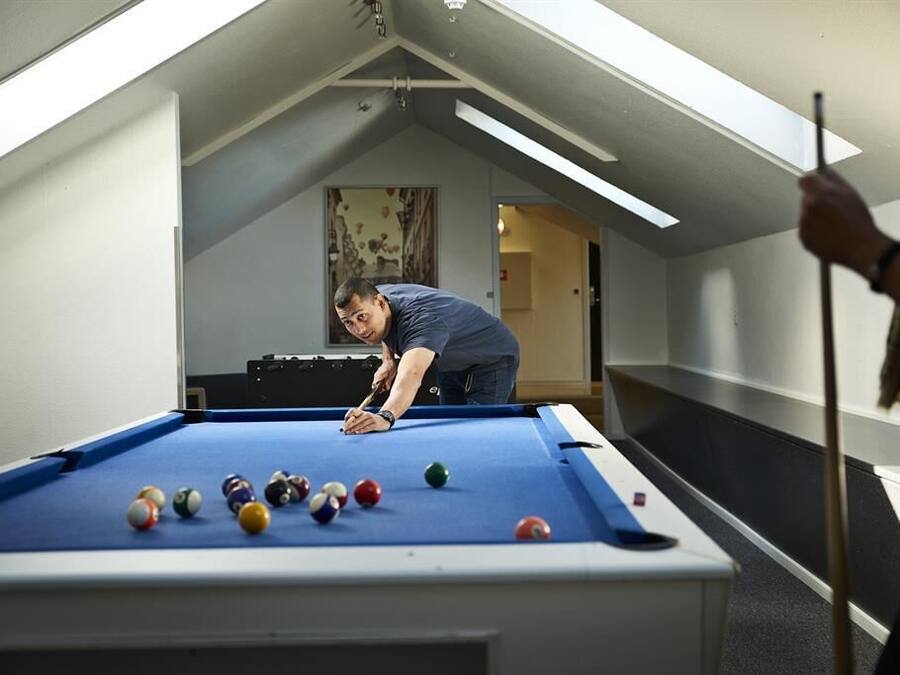 A pool table in a room with a sloped ceiling and skylights.
