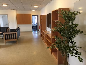 Ein geräumiges Zimmer mit einer langen Holzbibliothek, einer kleinen Sitzecke mit einer Bank und einem Blumentopf.