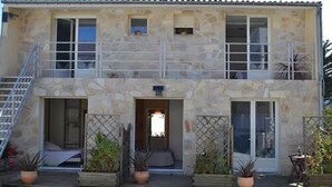 Un edificio in pietra a due piani con un balcone, una scala e piante in vaso.