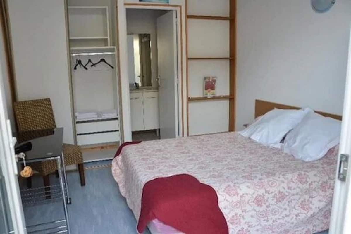 A bedroom with a bed, a wardrobe, a desk, and a chair.