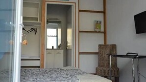 Una camera da letto con un letto, un armadio, una sedia e un televisore appeso al muro.