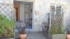 Un edificio in pietra con un patio in legno, piante in vaso e un'area salotto.