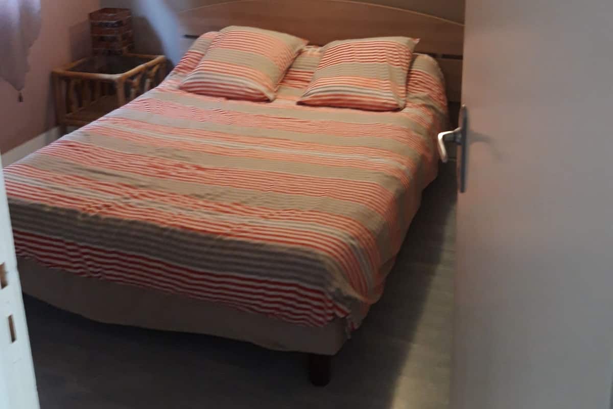 A bedroom with a bed, pillows, a nightstand, and wall-mounted lights.
