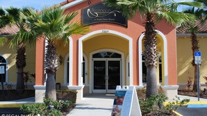 The exterior of Ascension Day Spa at Regal Palms Resort, featuring a yellow facade, palm trees, and a clear blue sky. - EPIC VALUE! Disney Retreat! Peter Pan! Resort! (Davenport)
