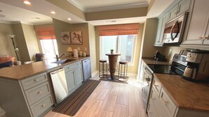 Una cocina con una isla central, electrodomésticos integrados y un comedor con mesa y taburetes.
