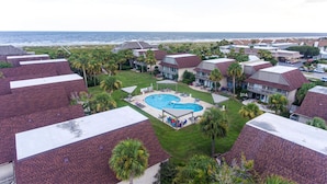Ein Resort mit mehreren bungalowartigen Gebäuden, einem zentralen Pool und Blick auf den Ozean.