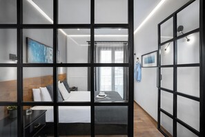 Une chambre d’hôtel moderne dotée d’un grand lit, d’une table de chevet, d’une armoire et offrant une vue à travers une paroi en verre.