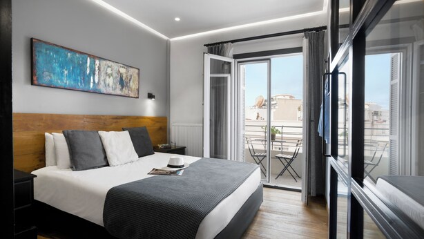 Ein modernes Hotelzimmer mit einem großen Bett, einem Nachttisch, einem Fenster mit Aussicht und einem Gemälde an der Wand.