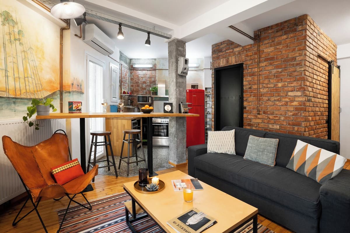 Un espace de vie moderne comprenant une cuisine, un coin repas et un espace détente avec un canapé et des fauteuils.