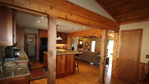 A spacious kitchen with wooden beams, a bar area, and a living room with a sofa and fireplace. - Luxury Mountain Cabin w/ Hot Tub 75 Private Acres, & Near New River (Jefferson)