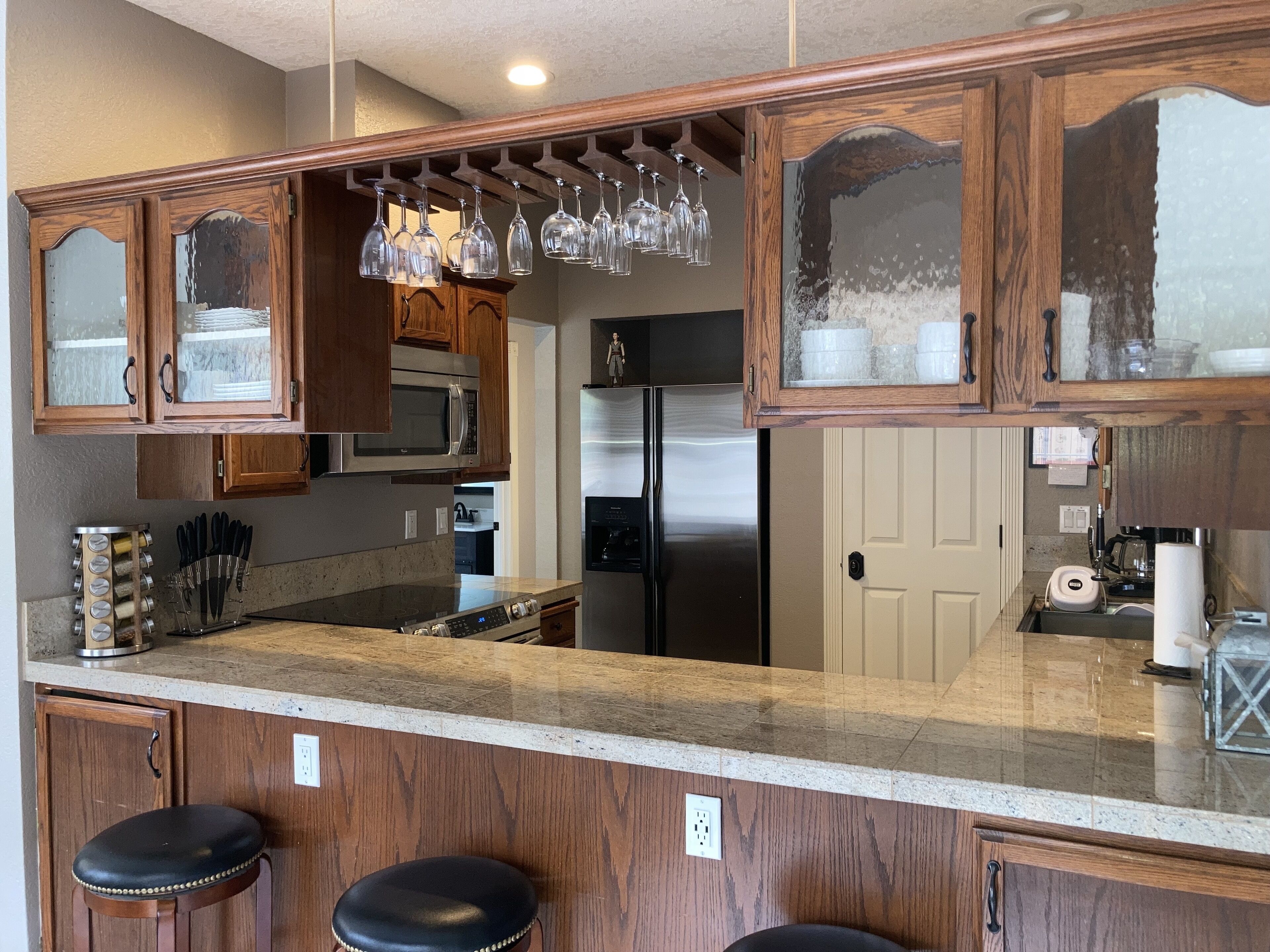 A kitchen with wooden cabinets, stainless steel appliances, and a bar area with stools.