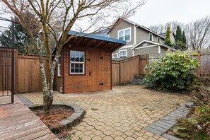 A wooden cabin with a metal roof, a brick patio, and a wooden deck.