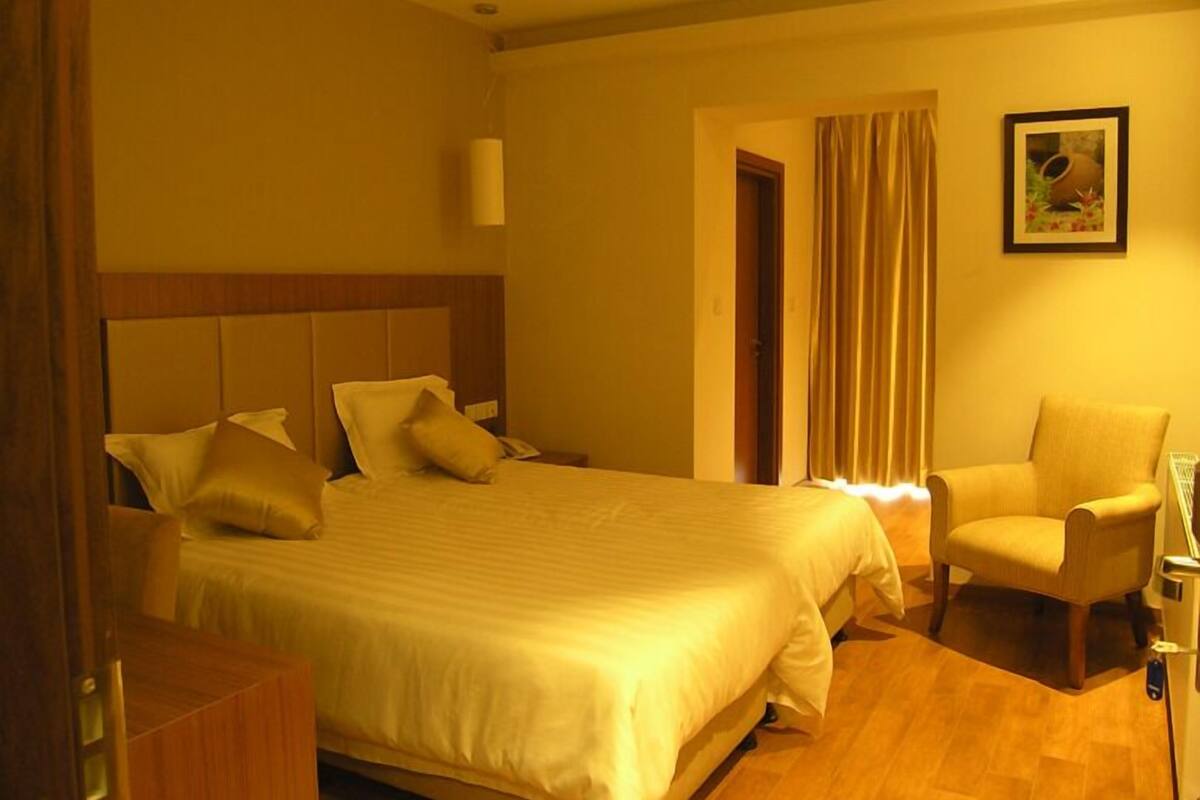 Een hotelkamer met een groot bed, een stoel en een schilderij aan de muur.