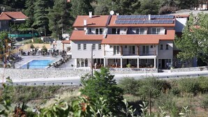Un edificio de dos plantas con piscina, paneles solares y balcón.