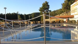 Una piscina con una barrera de cuerda, sillas de descanso y un edificio de piedra al fondo.