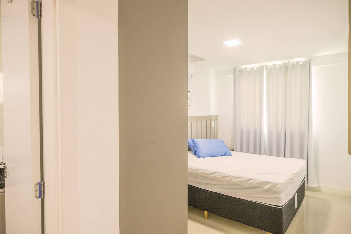 A bedroom with a bed, curtains, and a door.