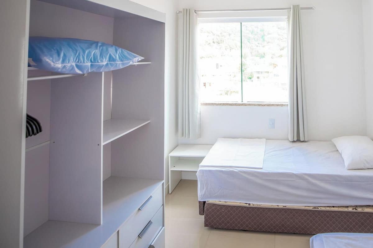 A bedroom with a bed, a desk, and a wardrobe.