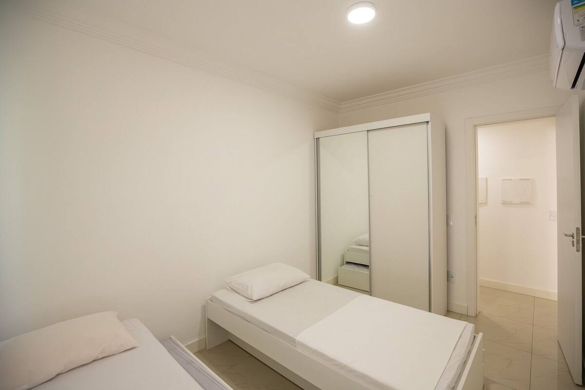 A bedroom with a single bed, a wardrobe, and a mirror.