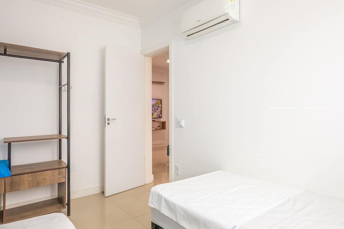 A bedroom with a bed, a wardrobe, and an air conditioning unit.