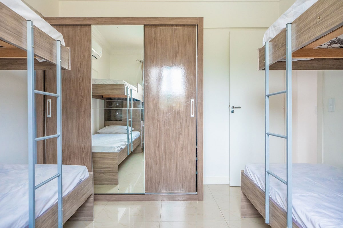 A room with bunk beds, a sliding door, and a visible bathroom with a shower and toilet.
