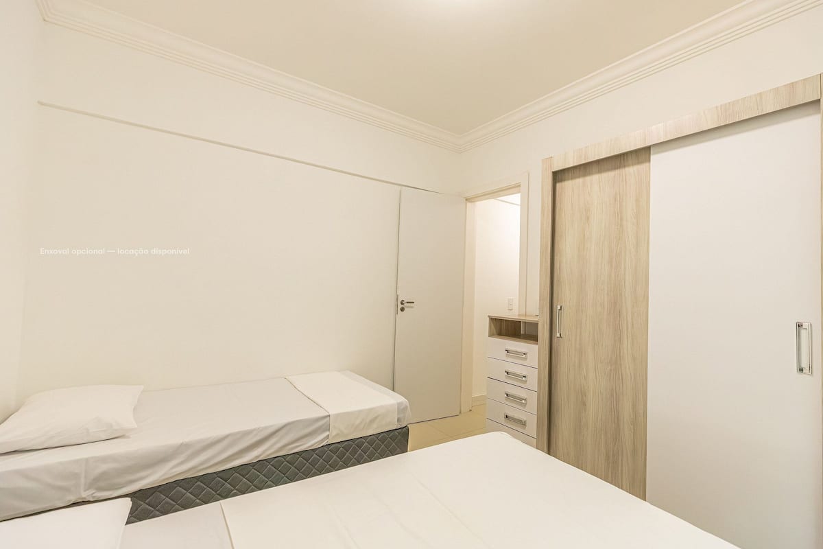A bedroom with two single beds, a wardrobe, and a dresser.