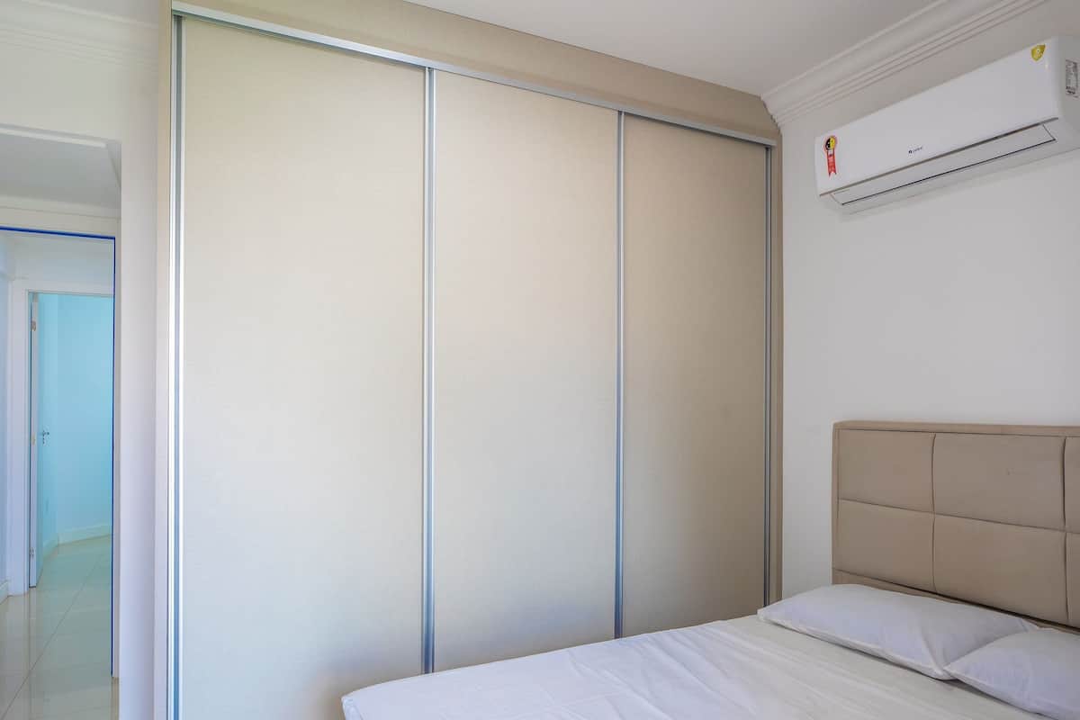 A bedroom with a bed, a sliding door, and an air conditioning unit.