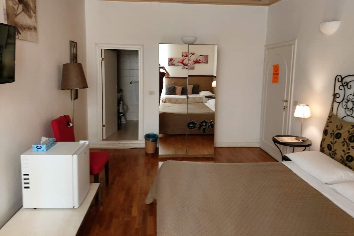 Ein Hotelzimmer mit Bett, Schreibtisch, Stuhl, Lampe und Kleiderschrank.