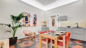 Eine moderne Küche mit Essbereich, mit einer großen Topfpflanze, einem Esstisch mit roten Stühlen und einer Küchenarbeitsplatte mit Spüle und Schränken.
