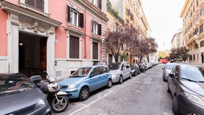 Eine schmale Straße gesäumt von parkenden Autos und historischen Gebäuden mit aufwendigen Fassaden.