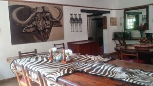 A dining area with a wooden table, zebra-patterned tablecloth, and chairs. There are decorative vases on the table. - Ruwa River Herbal Clinic & All-Inclusive Oasis Spa Resort (Harare)