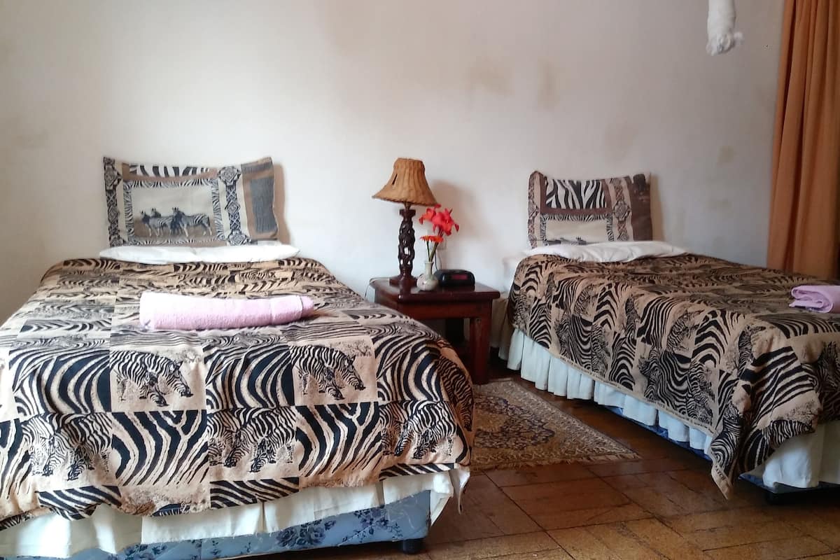 Habitación con dos camas, cada una con ropa de cama a rayas de cebra, una mesita con lámpara, y una lámpara colgante.