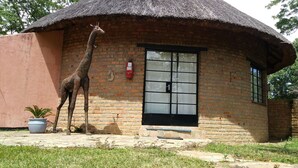 A brick building with a thatched roof, a giraffe statue, and a potted plant. - Ruwa River Herbal Clinic & All-Inclusive Oasis Spa Resort (Harare)
