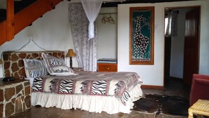 A bedroom with a stone wall, a bed with zebra-patterned bedding, a red chair, and a giraffe painting on the wall. - Ruwa River Herbal Clinic & All-Inclusive Oasis Spa Resort (Harare)