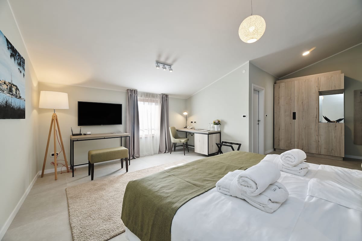 A modern hotel room with a bed, desk, chair, and a TV.