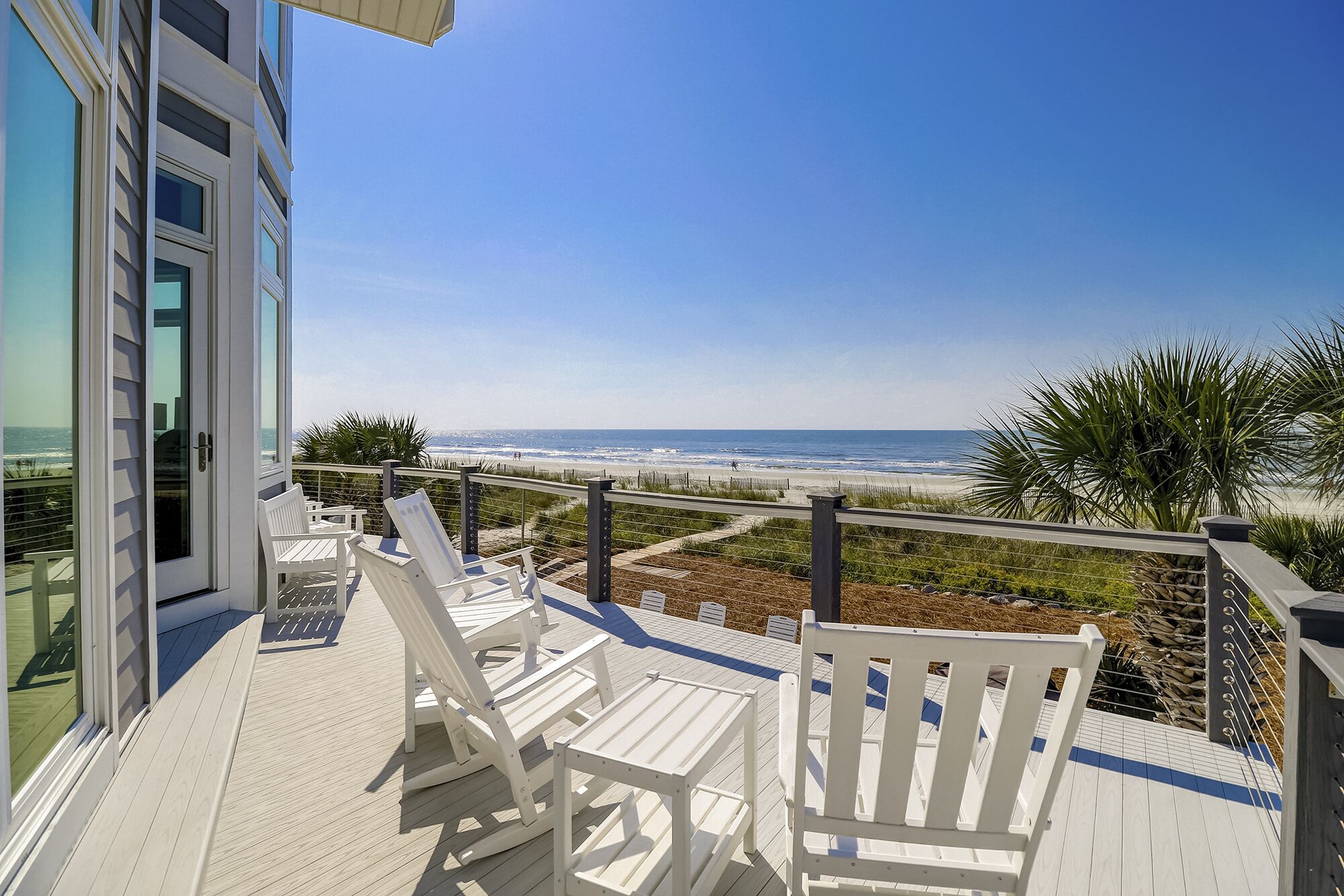 Een terras met witte stoelen met uitzicht op een strand.